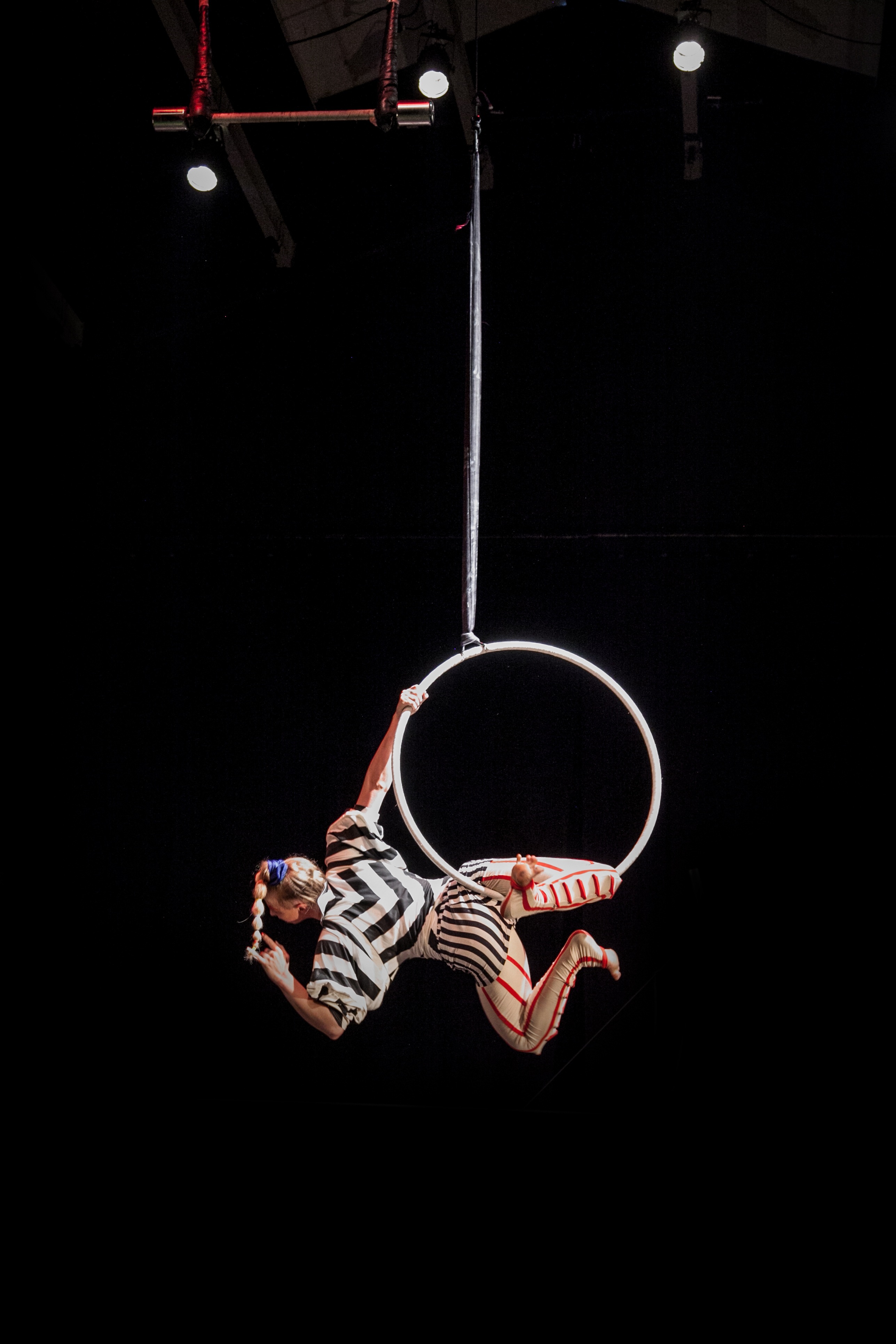 An aerial performer hanging from the bottom bar in the lyra (aerial hoop).